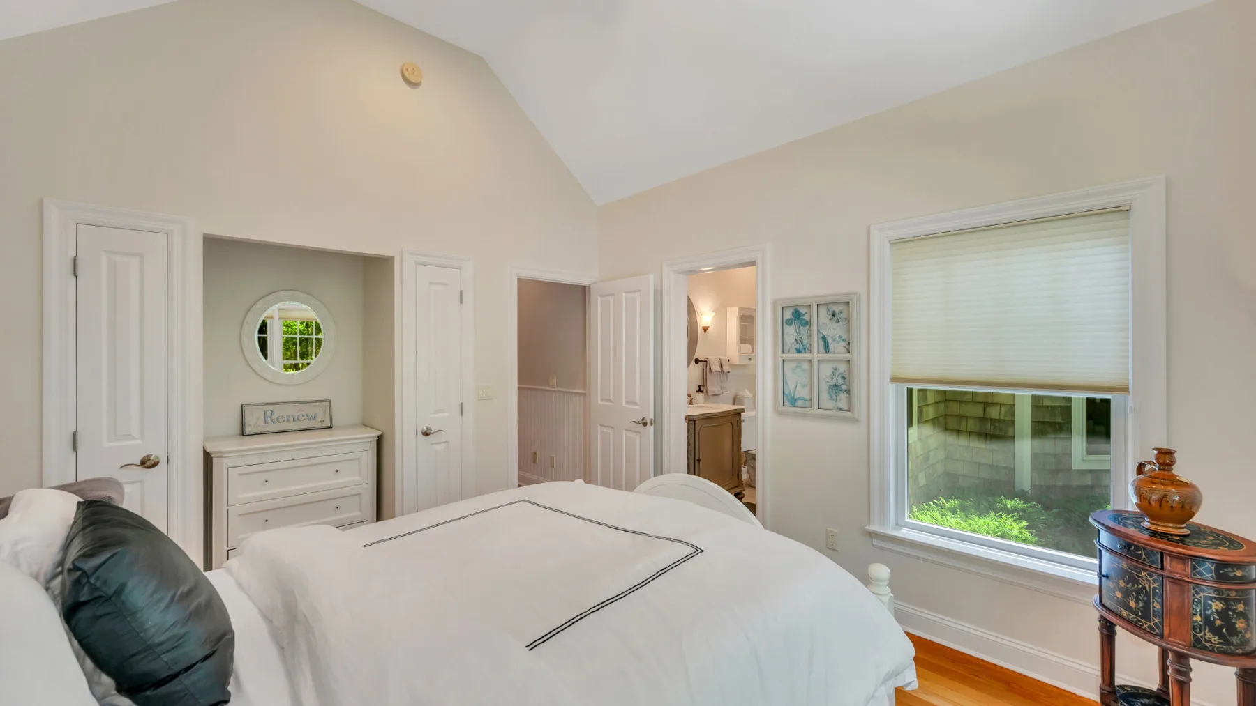 Un dormitorio luminoso con una cama bien hecha y una ventana grande.