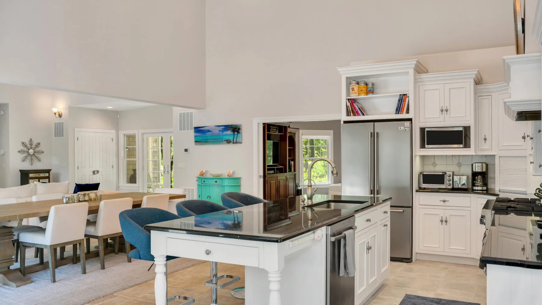 Cocina y comedor de concepto abierto con una isla central y muebles blancos.