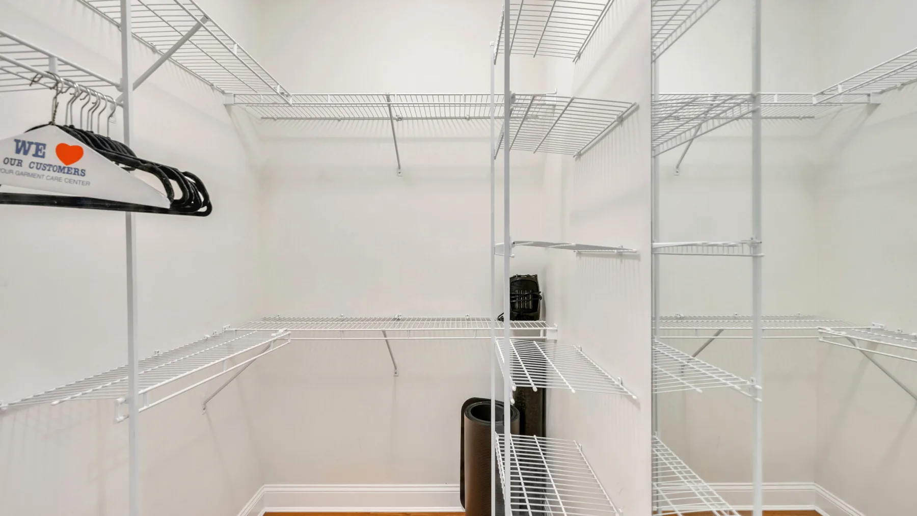 Un vestidor blanco con estantes de alambre y espacio para colgar ropa.