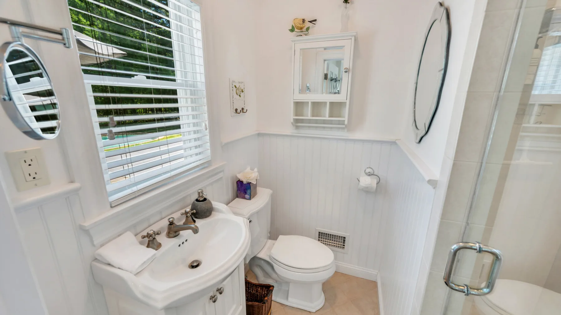 Un baño luminoso con lavabo, inodoro y ducha de vidrio.