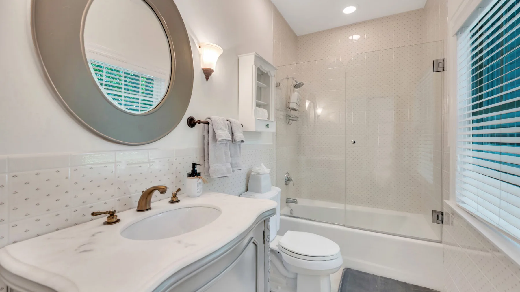 Un baño luminoso con lavabo, inodoro y ducha con mampara de vidrio.