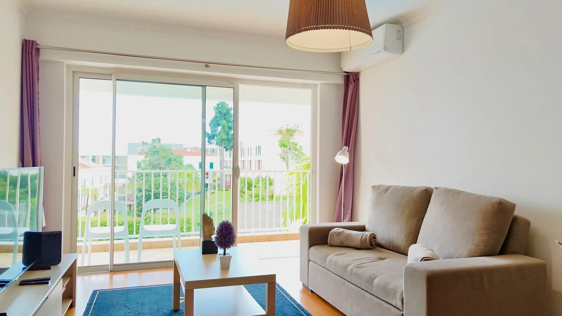 Una sala de estar con asientos junto a grandes puertas de cristal que dan a un balcón.