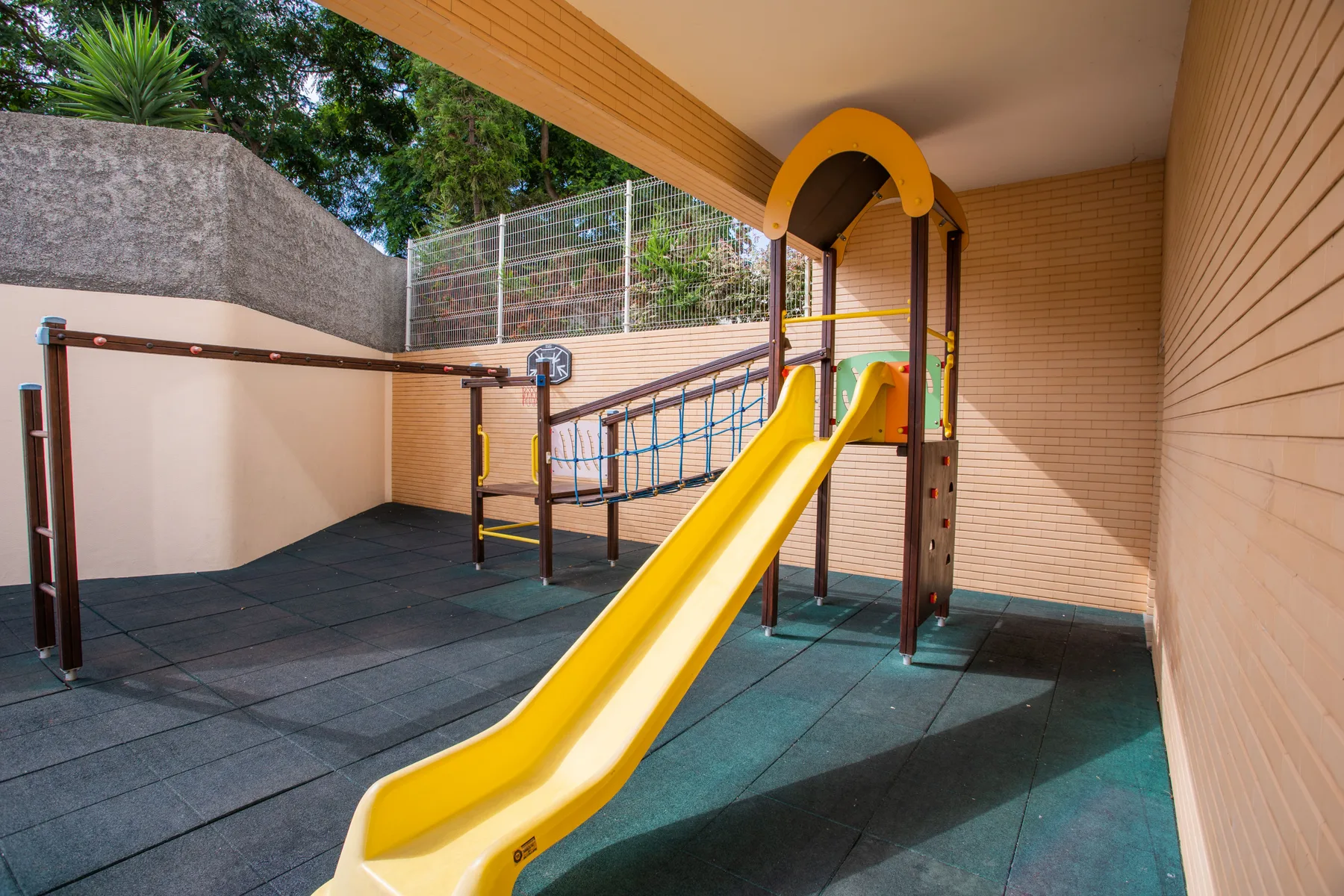 A covered play area with a yellow slide and climbing structure.
