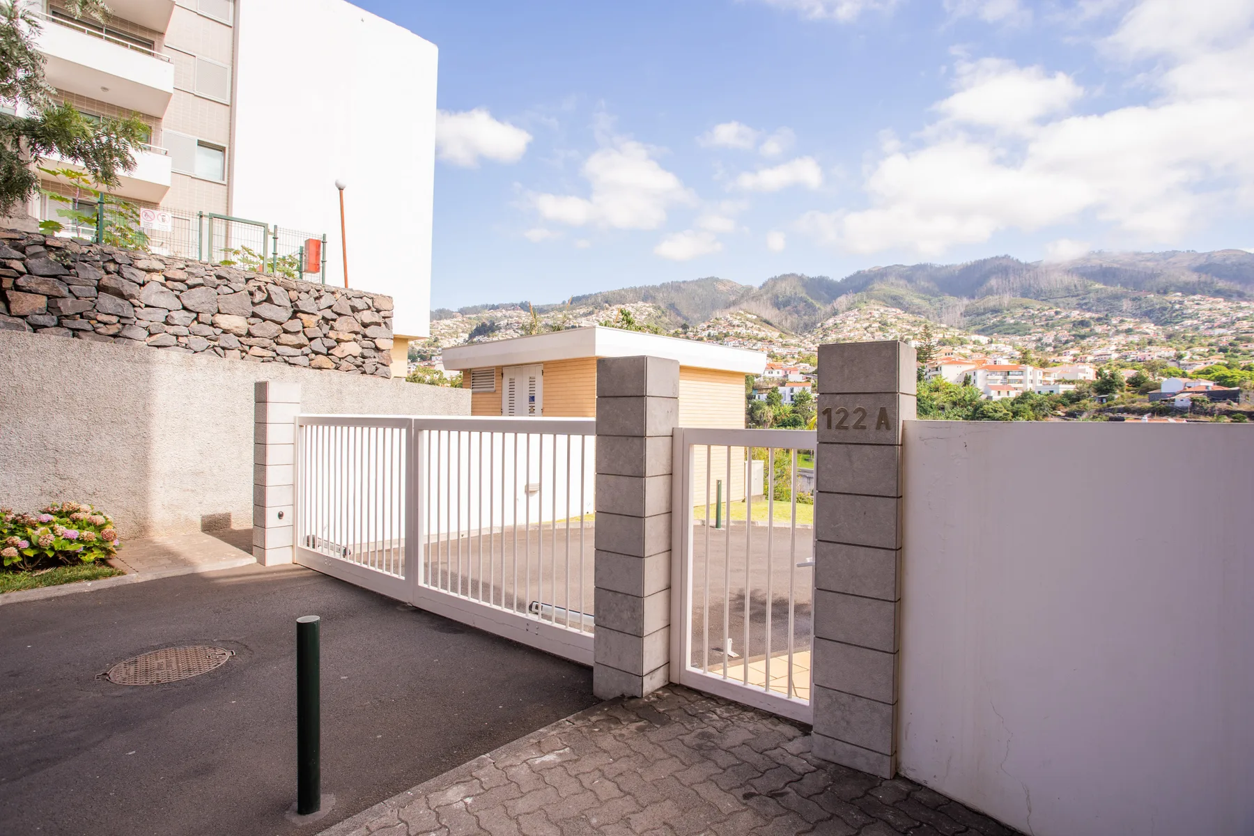 An apartment entrance with a metal gate, paved driveway, and mountain views.