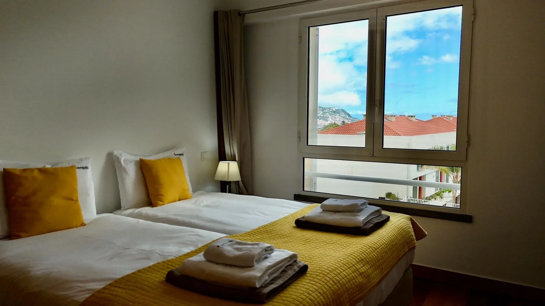 Un dormitorio con dos camas, toallas dobladas y una ventana grande.