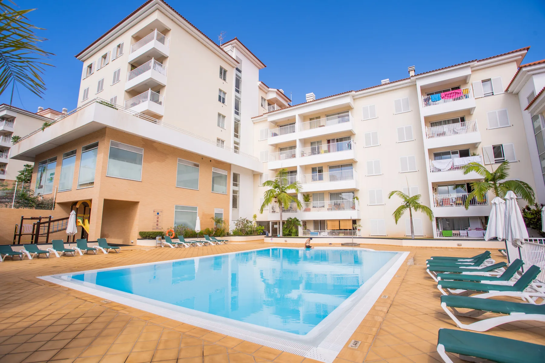 Una piscina al aire libre está en un patio rodeado de edificios de apartamentos.