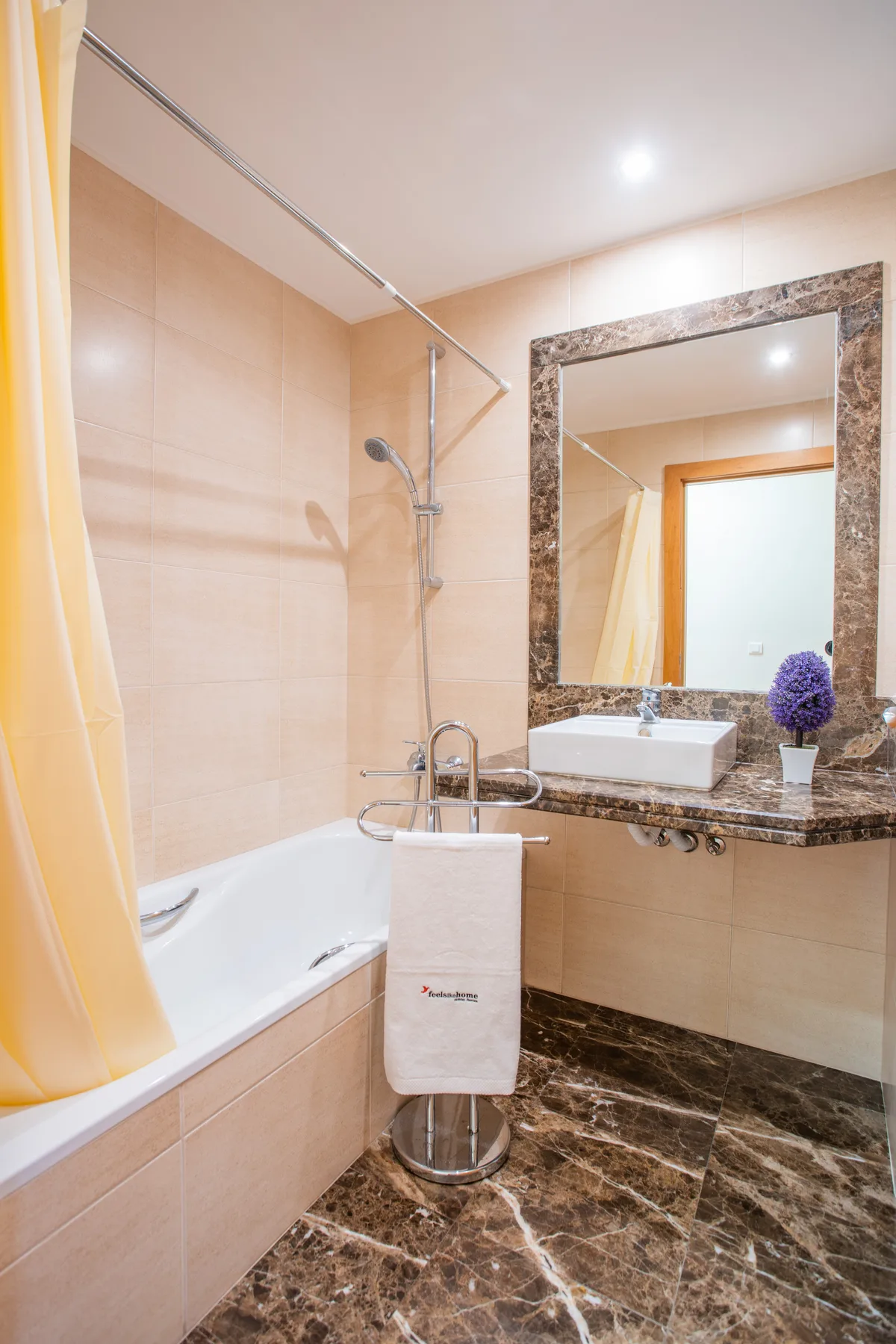 A tiled bathroom with a bathtub, shower, and sink beneath a large mirror.