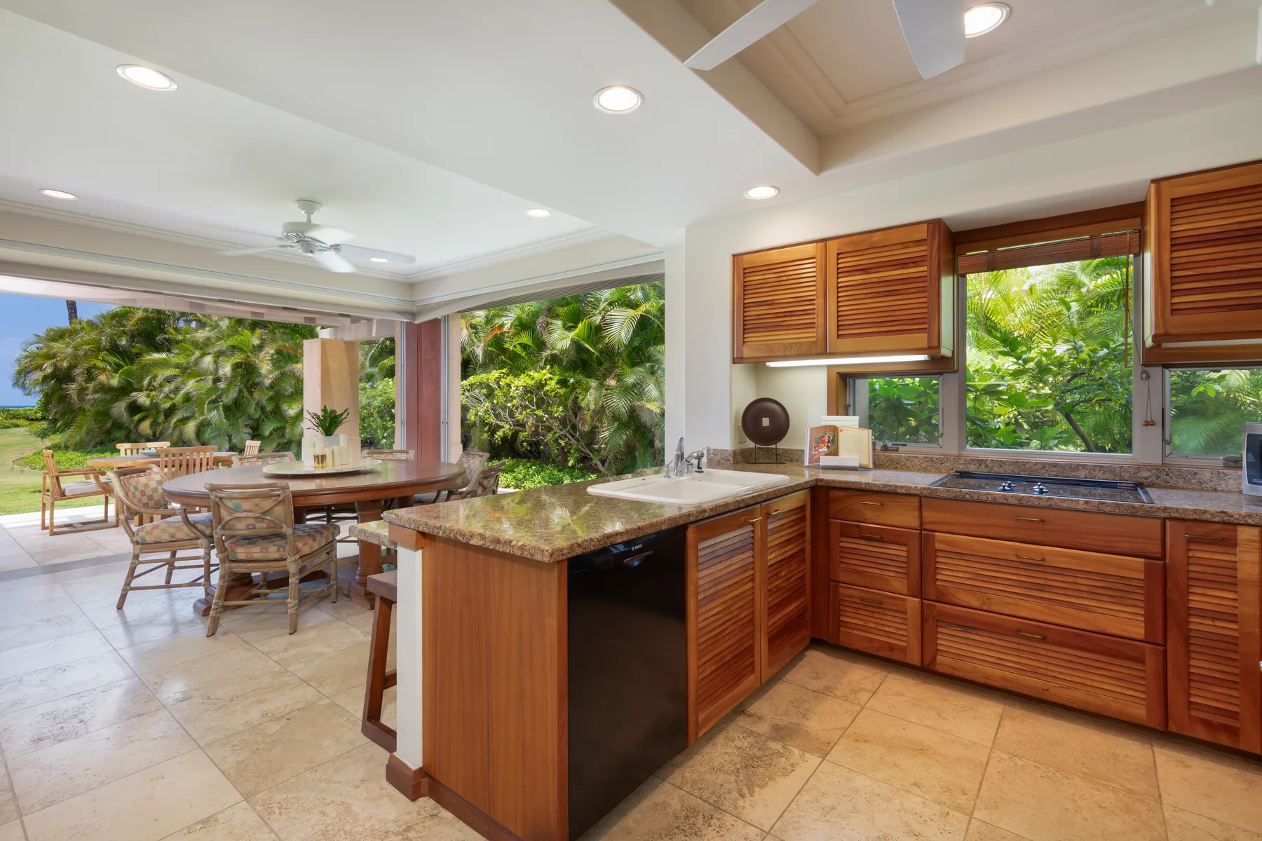 An open kitchen with wooden cabinetry and a dining table beside the patio.