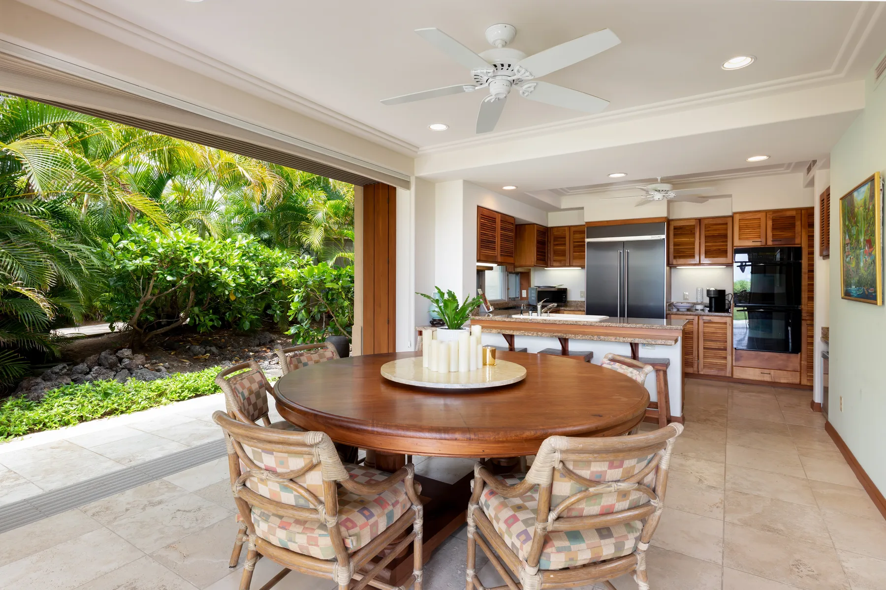 An open dining area with a round wooden table and a kitchen beyond.