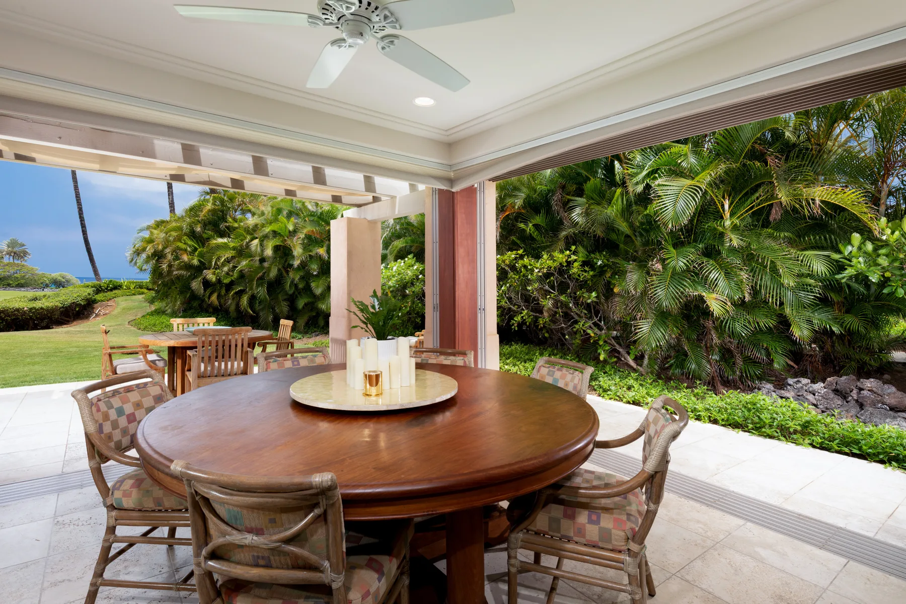 A covered outdoor dining area with a round table and garden views.