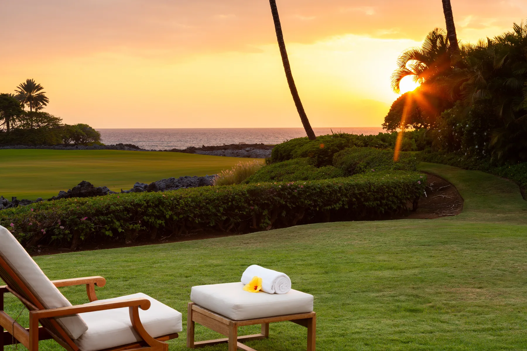 A garden seating area overlooks the ocean at sunset.