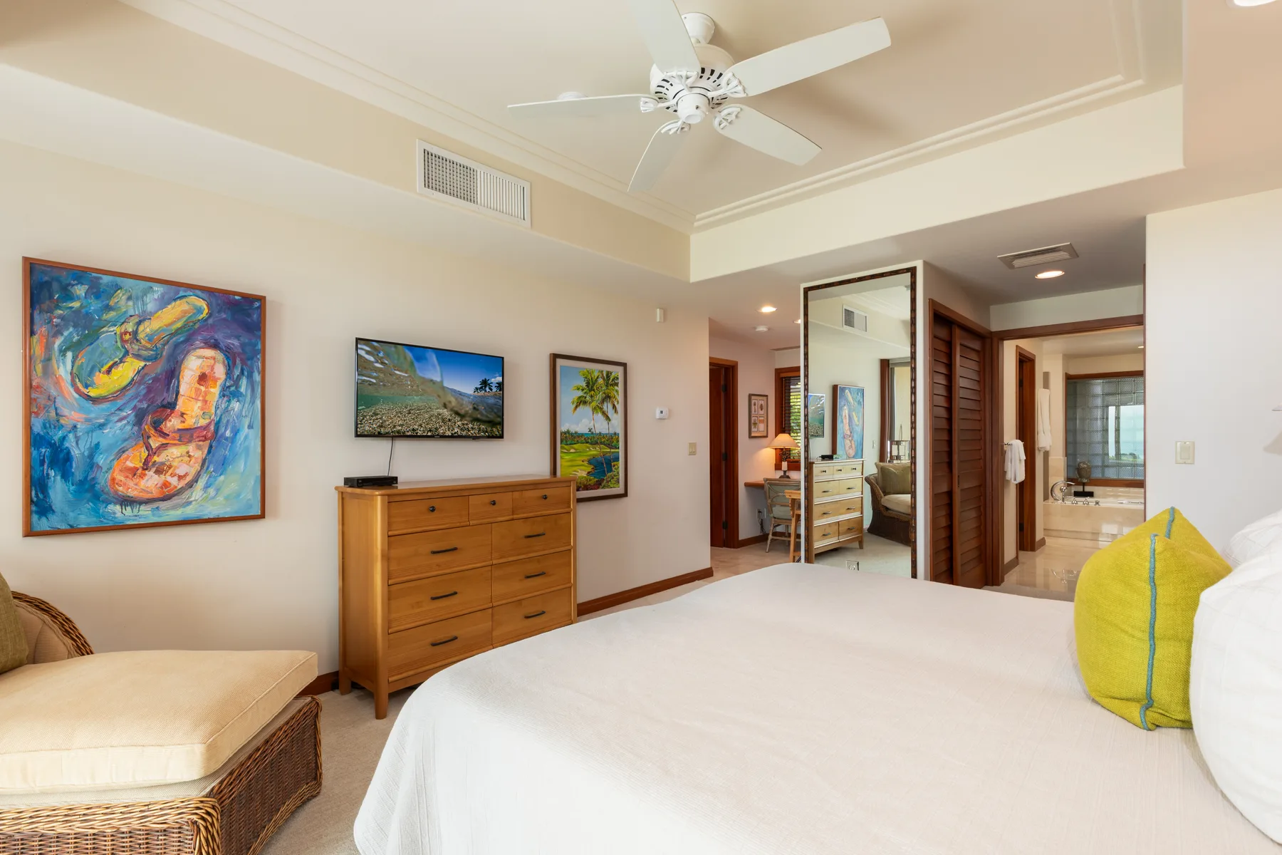 A bedroom with a bed, dresser, and colorful wall art.