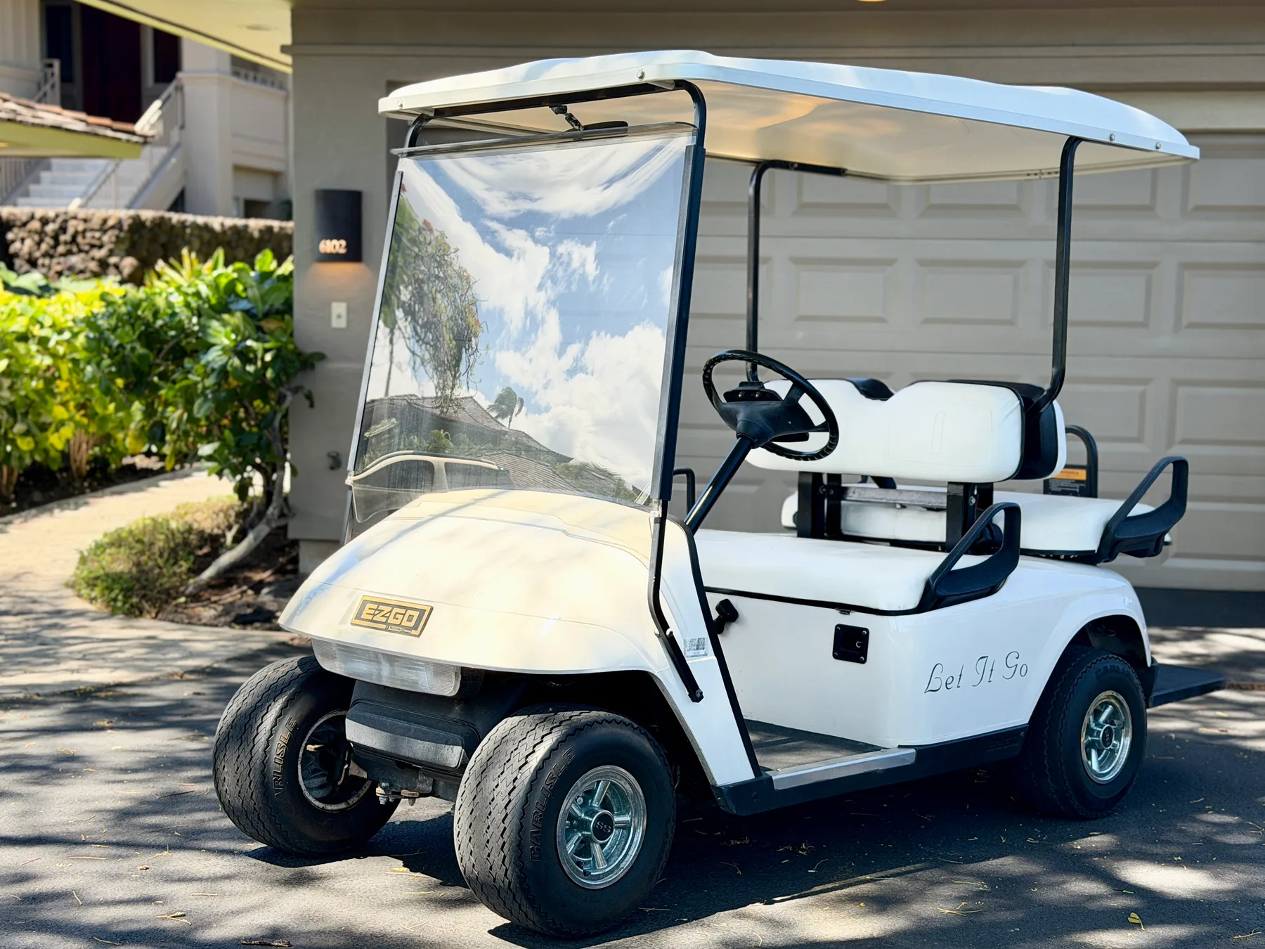 A white golf cart is parked in front of a garage.
