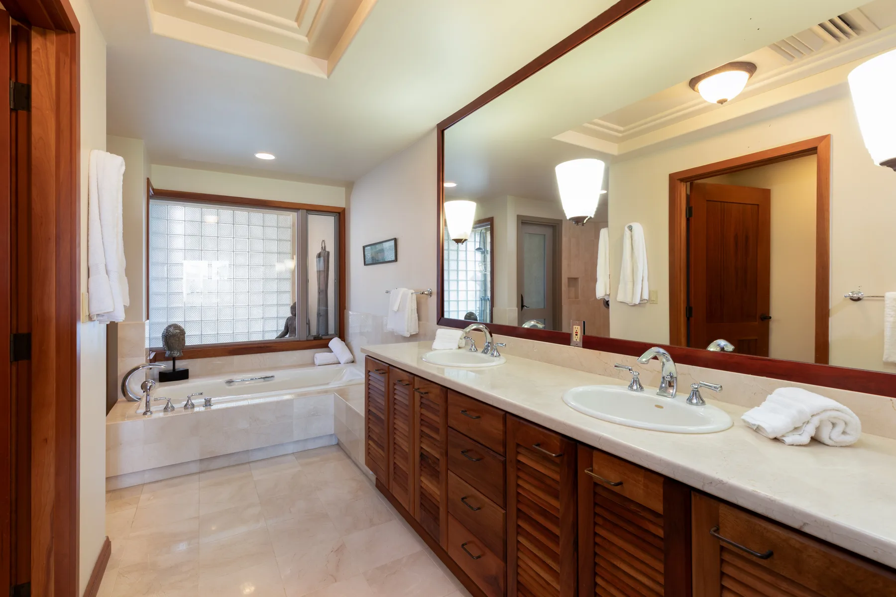 A spacious bathroom with a long vanity, large mirror, and bathtub.