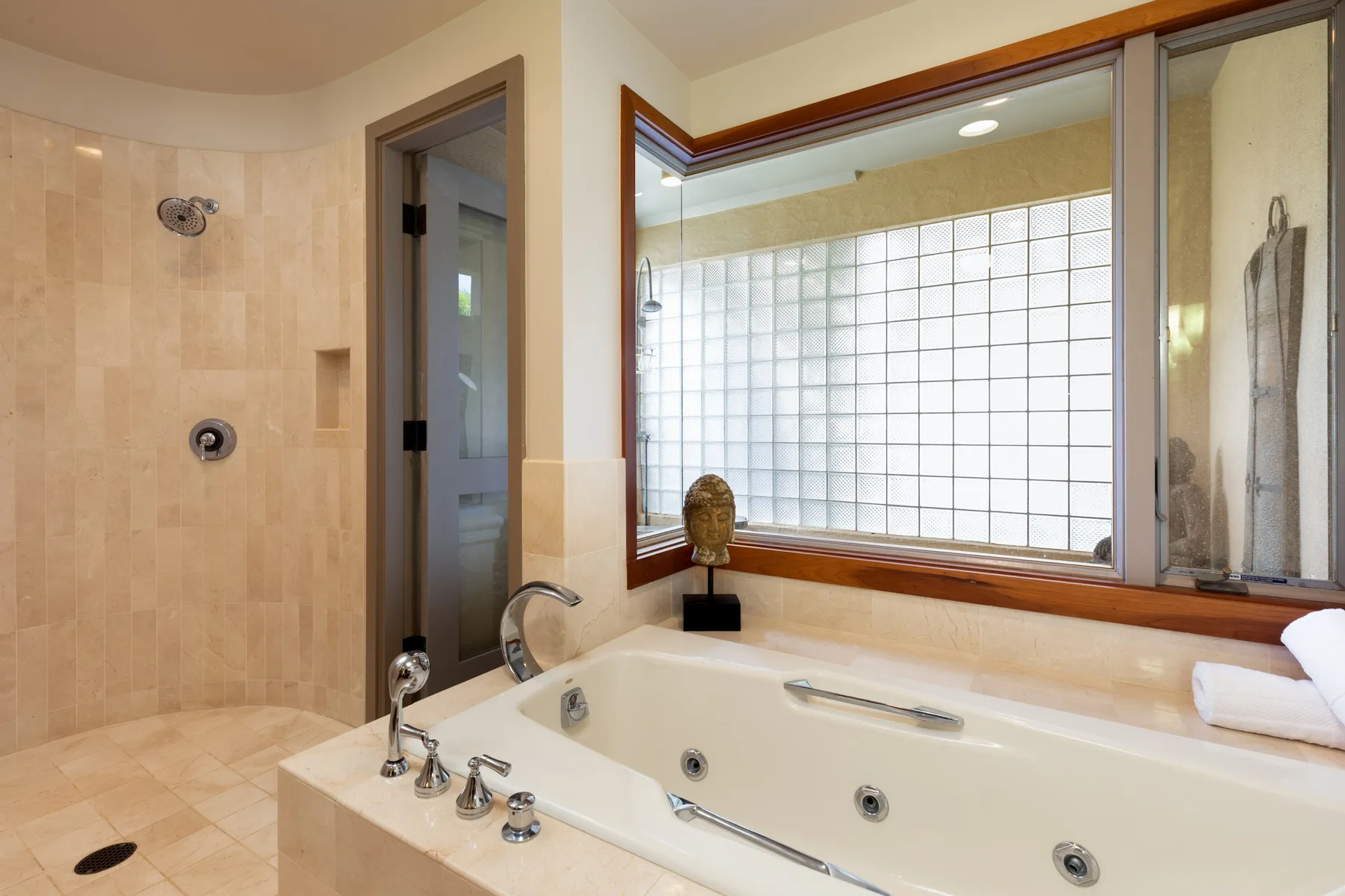 A tiled bathroom features a large soaking tub beneath a wide window.