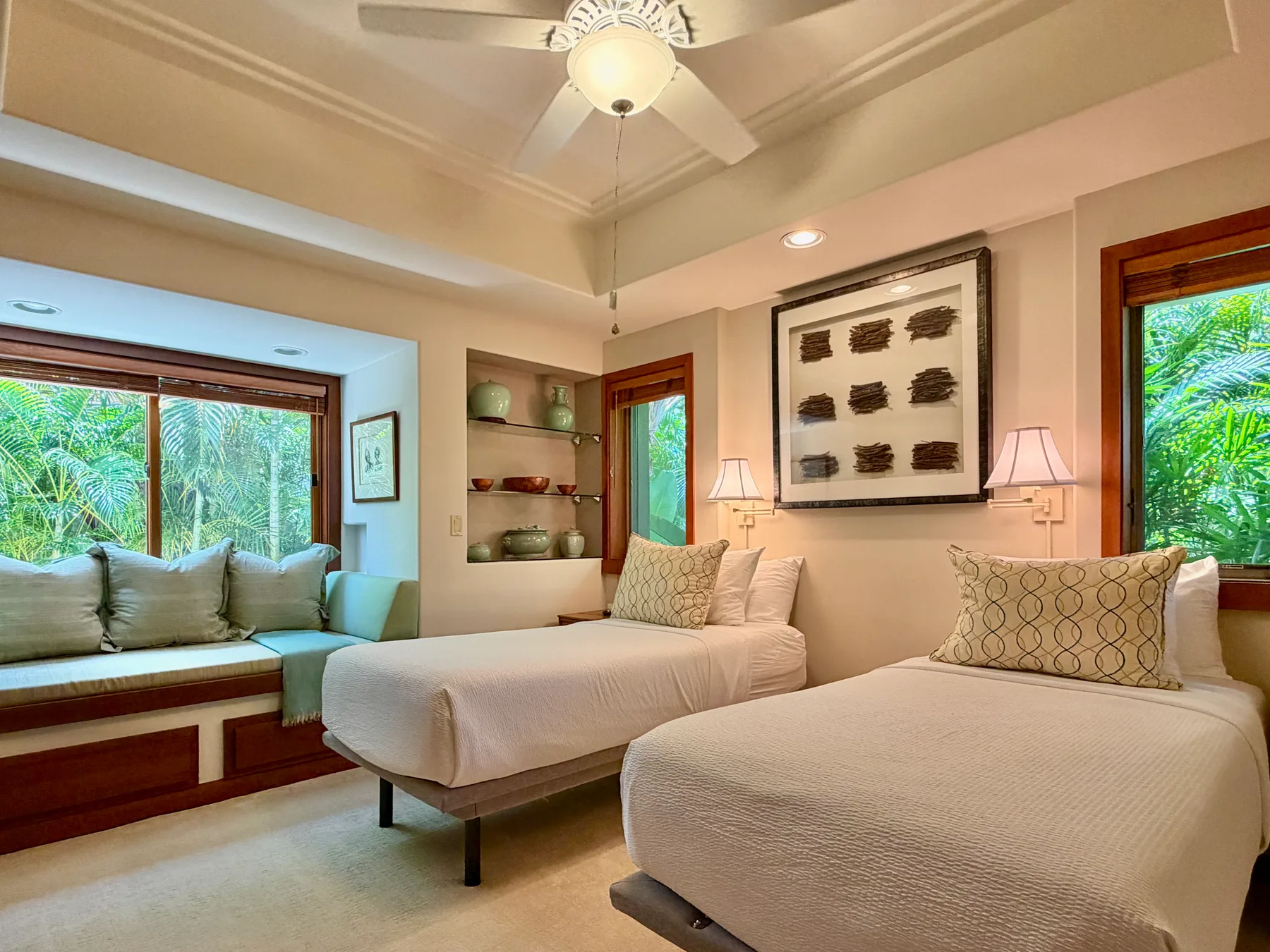 A bedroom with two beds and a window overlooking greenery.
