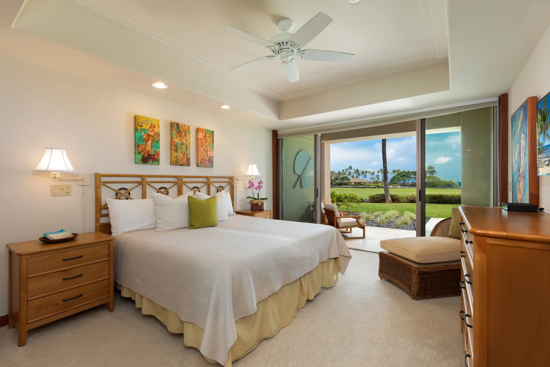 A bedroom with a large bed and sliding glass doors opening onto a garden view.
