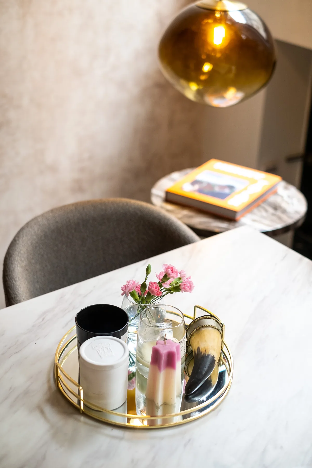 A dining area features a round table with a tray of candles and flowers.