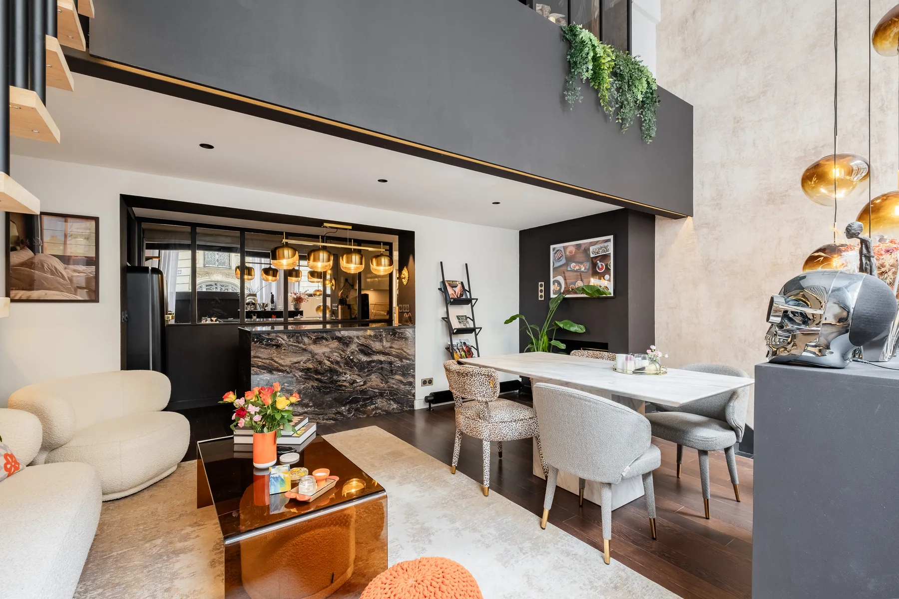 A modern dining area with a long table, upholstered seating, and a counter in the background.