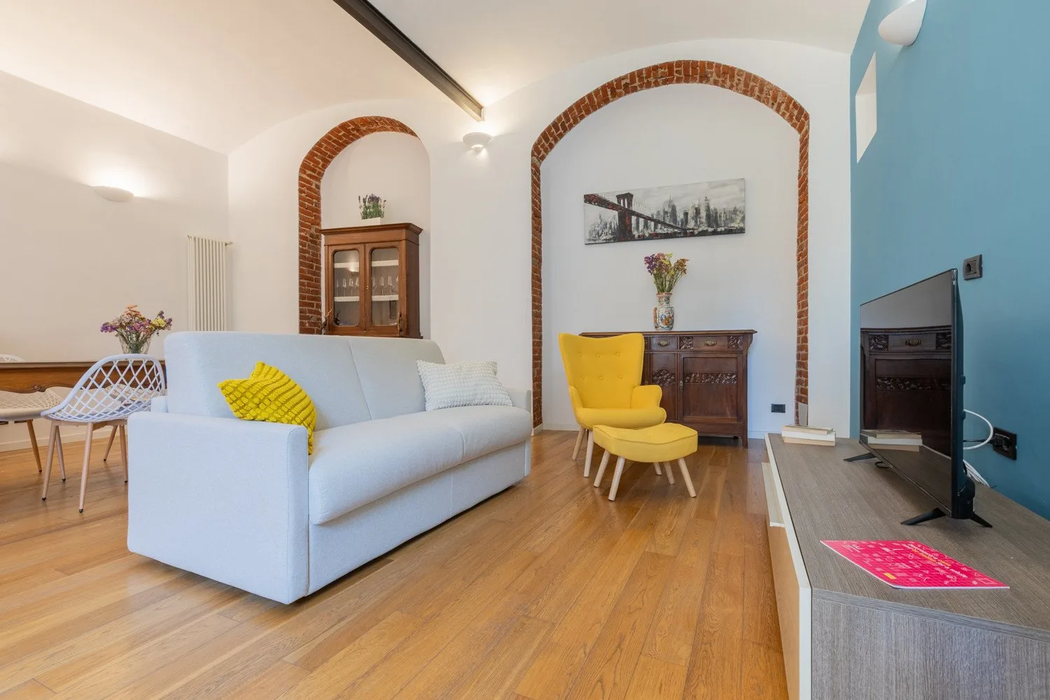 A bright living room with a white sofa and yellow accent chair.
