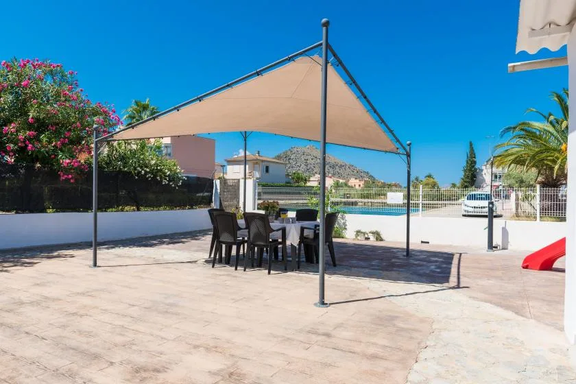 An outdoor patio with a table and seating beneath a shade canopy.
