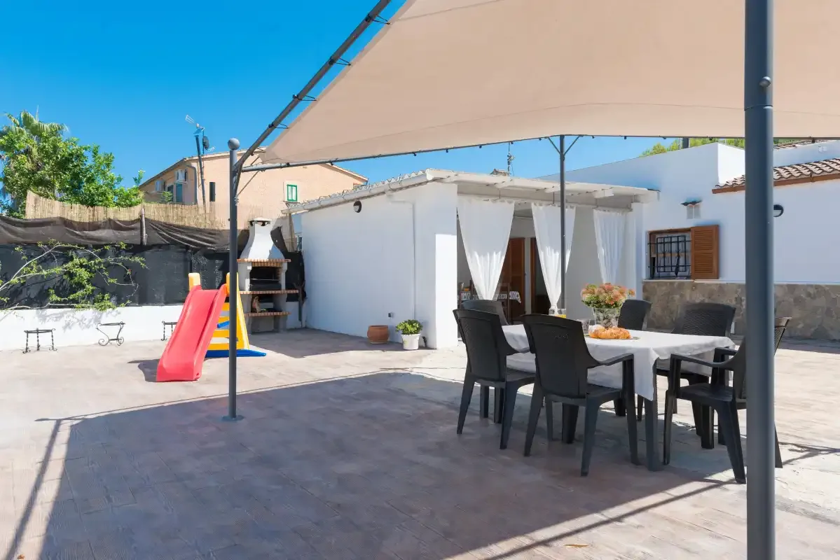 A sunny outdoor patio with a dining table and a children’s slide.