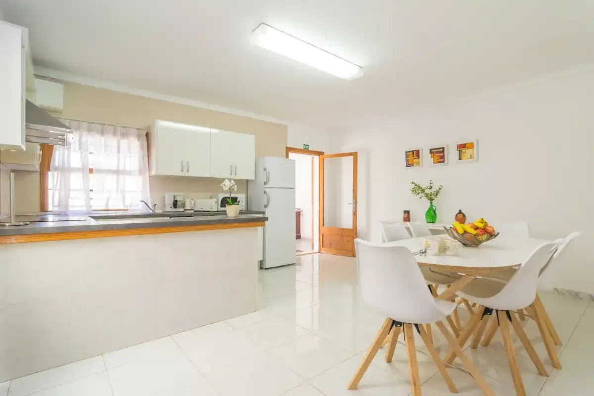 A bright kitchen and dining area with a counter, table, and chairs.