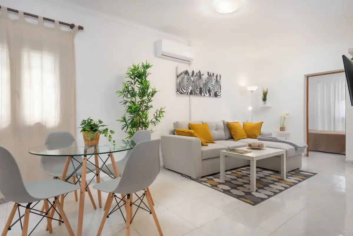 Bright living room with a seating area, dining table, and large windows.