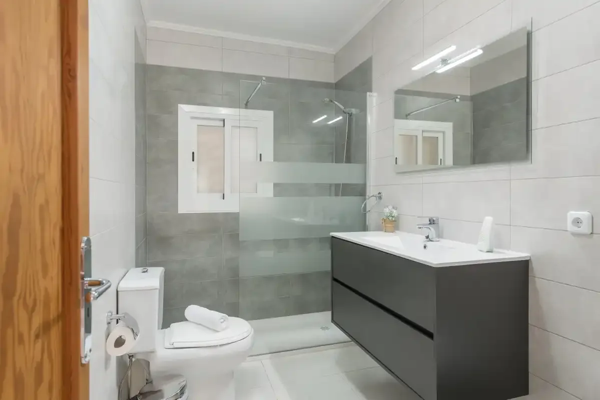 A modern bathroom with a glass shower, vanity, and toilet.