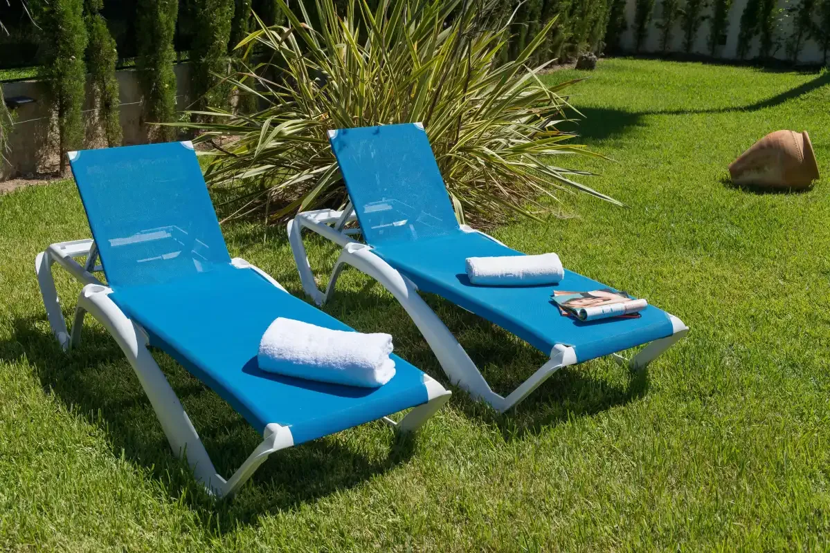 Two blue sun loungers with folded towels sit on a grassy lawn.