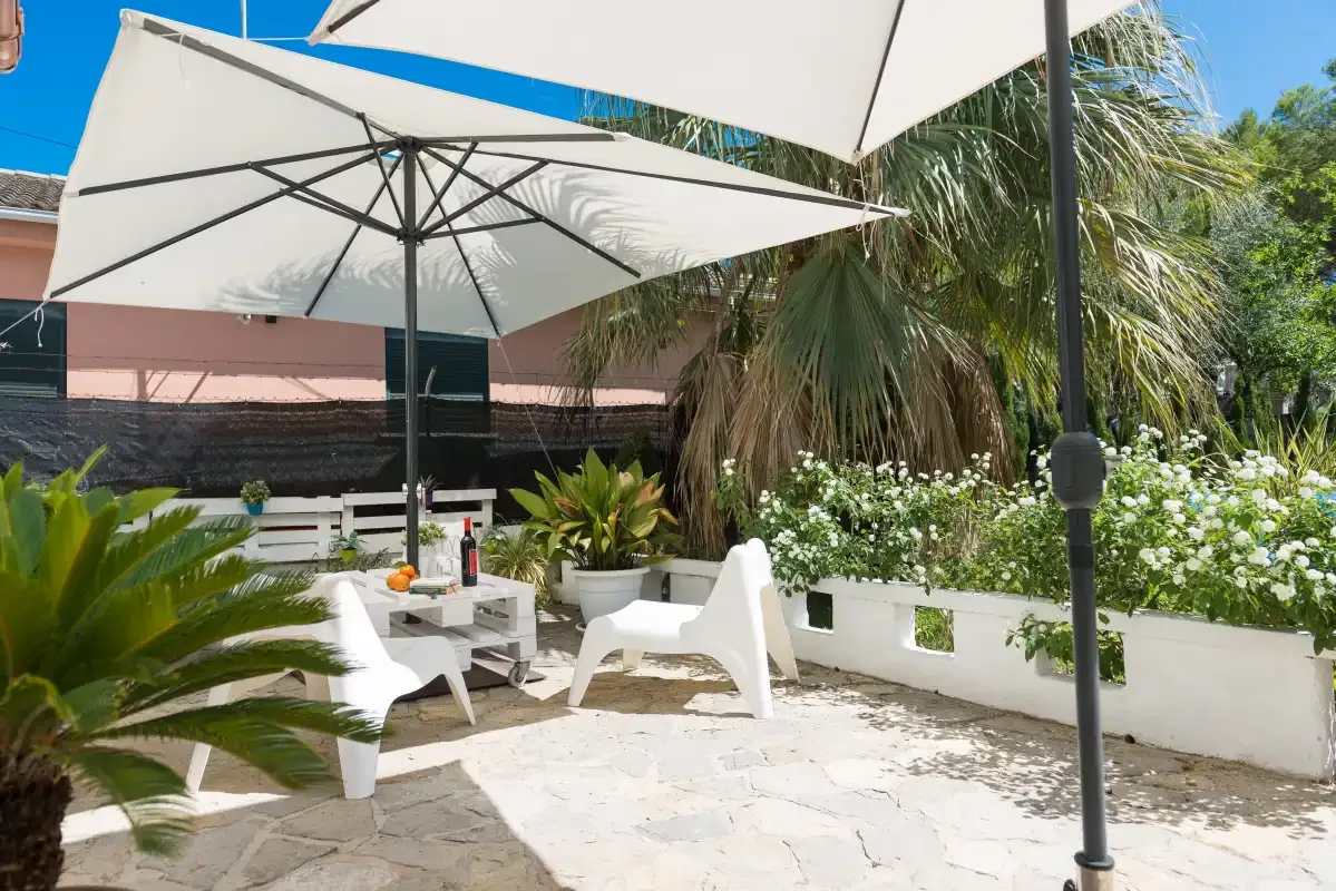 An outdoor patio with white seating beneath large shade umbrellas.
