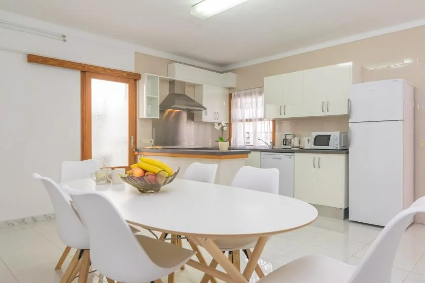 A bright kitchen and dining area with a white table and kitchen cabinets.