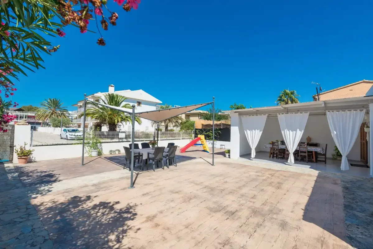An outdoor patio has shaded seating and a curtained dining area.