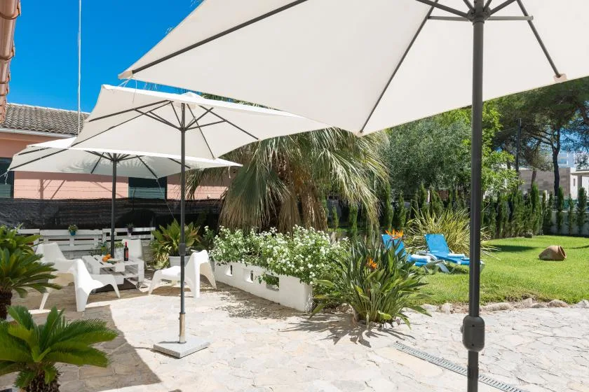 An outdoor patio with white umbrellas, seating, and a landscaped garden.