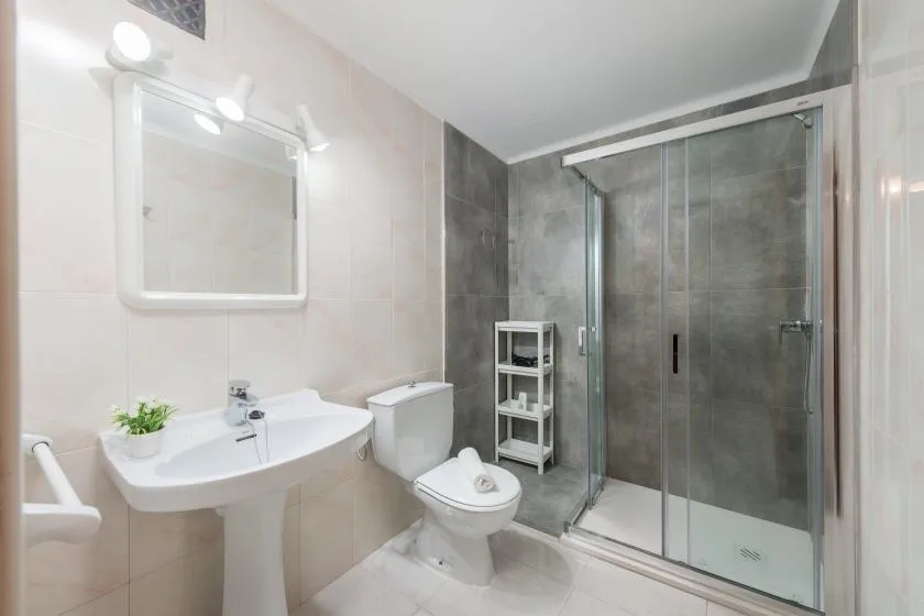 A bathroom with a sink, toilet, and glass shower.