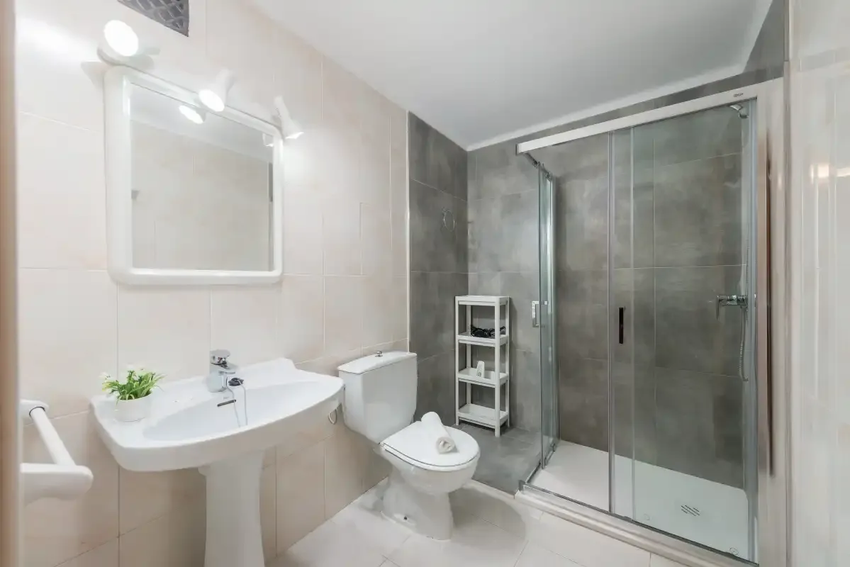 A tiled bathroom with a sink, toilet, and glass-enclosed shower.