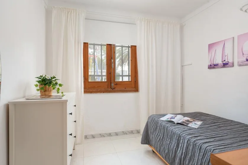 A bedroom with a bed beside a curtained window.