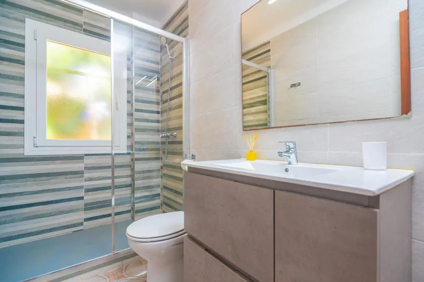 A bathroom with a glass shower, toilet, and sink vanity.