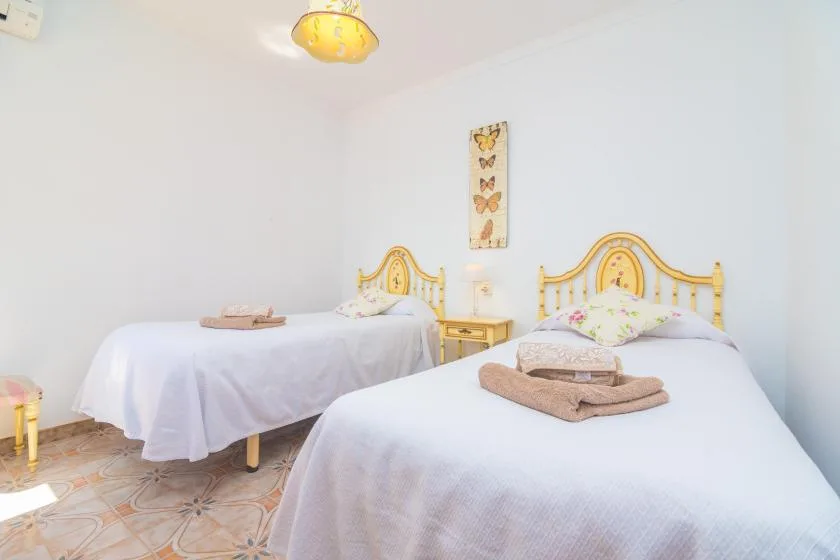 A bedroom with two beds dressed in white linens and light wood headboards.