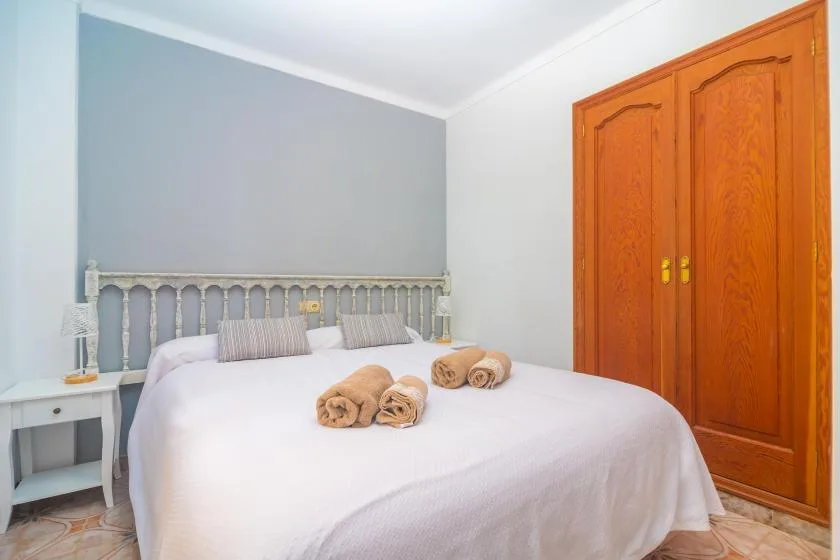 A bedroom with a made bed and a wooden wardrobe.