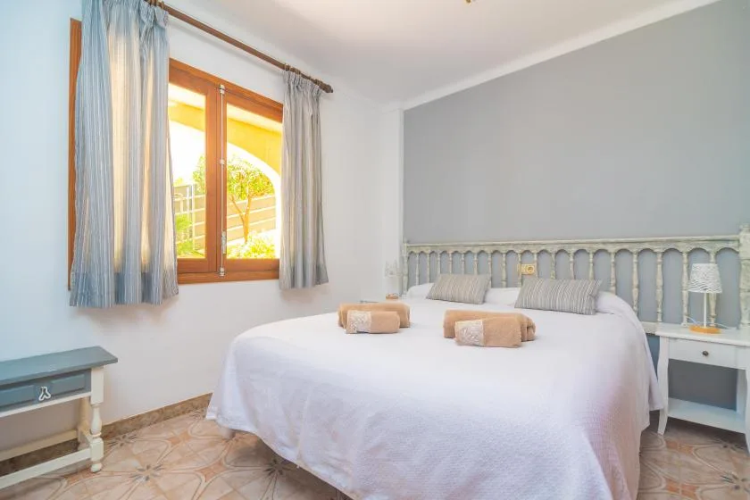 A bedroom with a large bed, striped curtains, and a sunlit window.