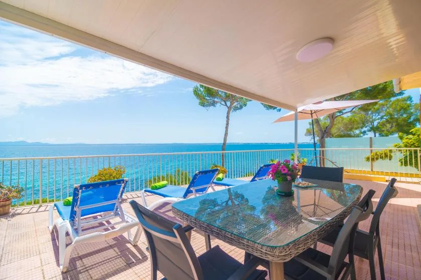 Una zona de comedor al aire libre con mesa y asientos da al mar.