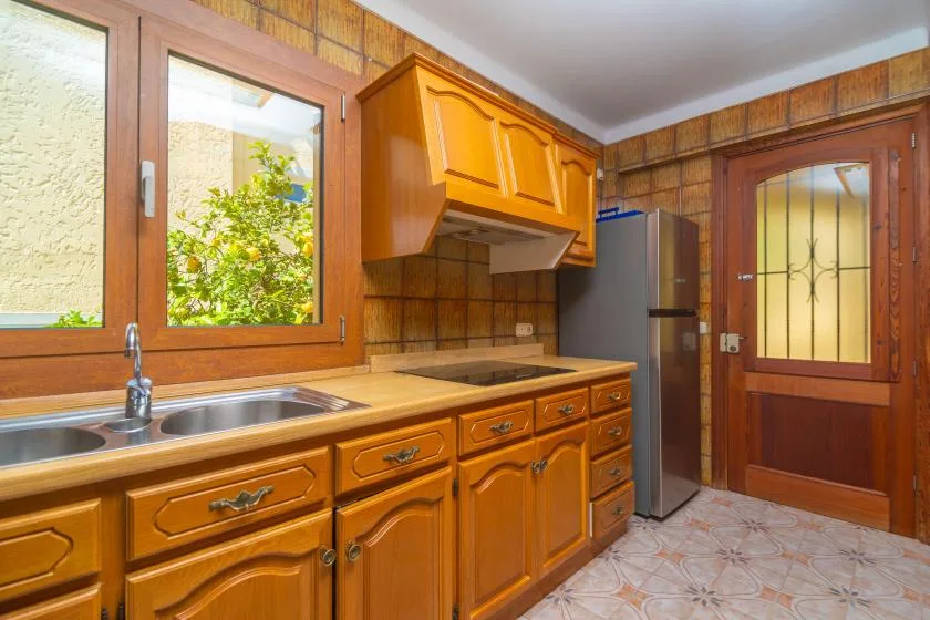 A compact kitchen with wooden cabinetry, a countertop, and a window.