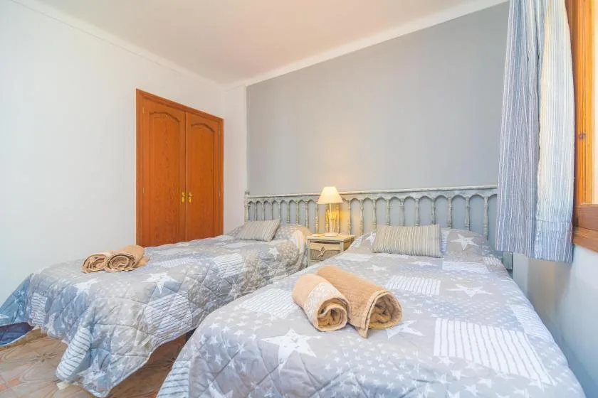 A bedroom with two beds, patterned bedding, and a small bedside lamp.