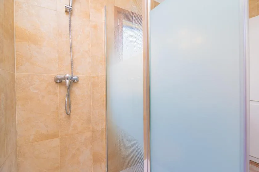 A tiled bathroom shower with a frosted glass screen.