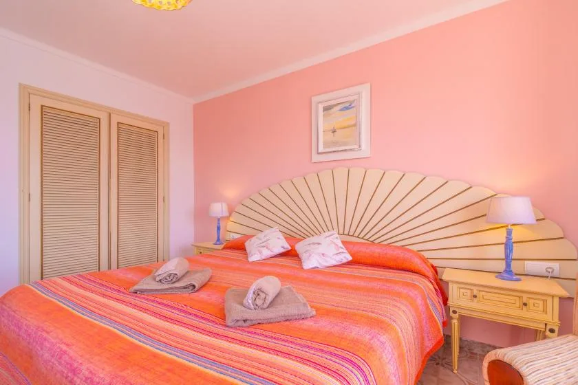 A bedroom with a colorful striped bedspread and a fan-shaped headboard.