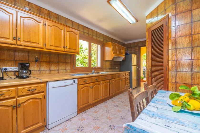 A wood-paneled kitchen with wooden cabinets, a refrigerator, and a dining table.