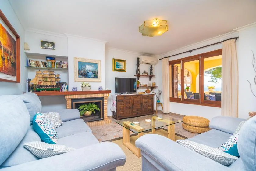 A bright living room with seating, a glass coffee table, and a large window.
