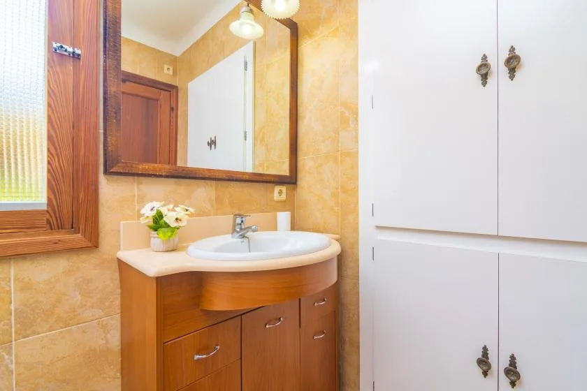 A bathroom vanity with a sink, mirror, and white storage cabinets.