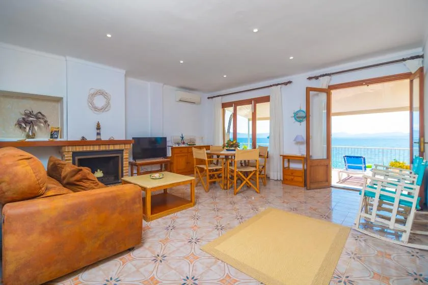 A living room opens onto a balcony with a view of the sea.